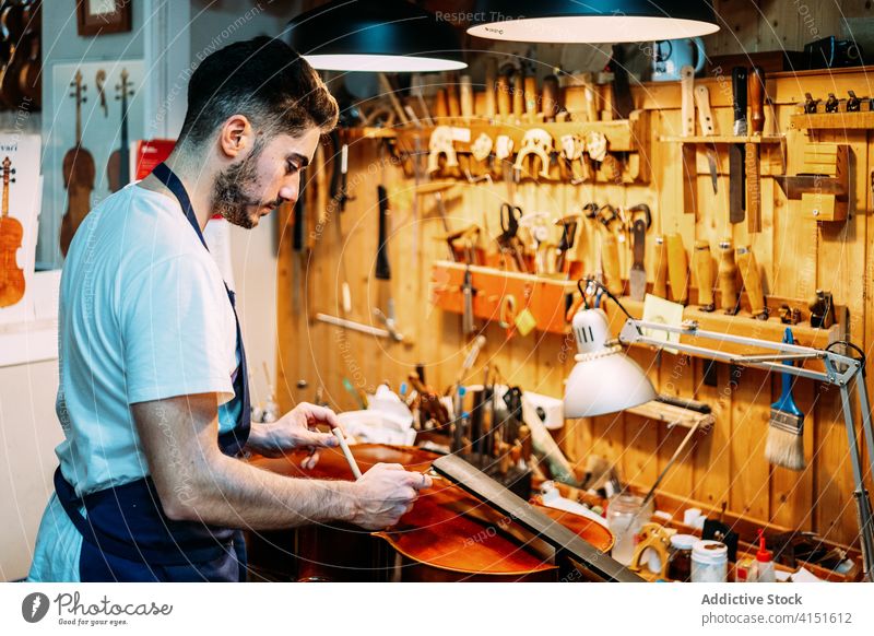 Geigenbauer beim Einbau des Stimmstocks in die Geige Zupfinstrumentenmacher Klang einstecken installieren machen Instrument Kunstgewerbler Handwerk Werkzeug