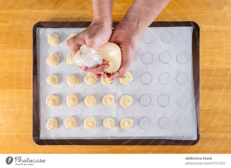 Gesichtsloser Koch, der Teig auf ein Backblech spritzt Bäcker Gebäck Backwarenbeutel Röhren Prozess drücken Bäckerei professionell Kleinunternehmen heimwärts