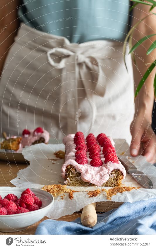 Frau bei der Zubereitung eines Desserts mit Himbeeren Kuchen Gebäck Sahne Glasur vorbereiten Lebensmittel süß machen Hausfrau Küche Koch lecker geschmackvoll