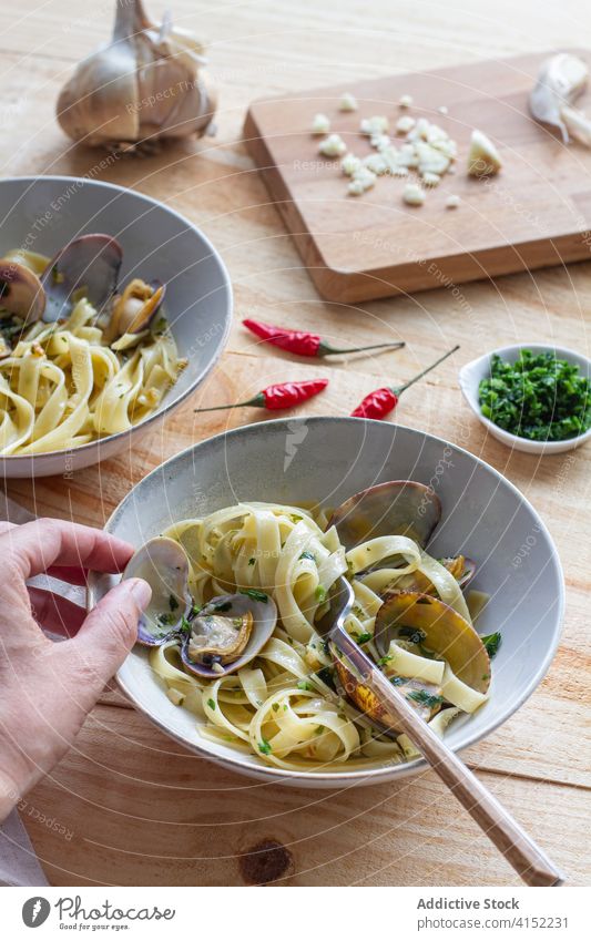 Erntekoch bei der Zubereitung von Tagliatelle Alle Vongole Tagliatelle alle vongole Speise vorbereiten Koch Küchenchef Spaghetti Molluske Muschel Tisch Café