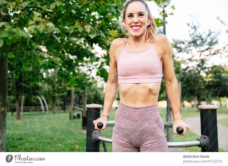 Fröhliche, fitte Frau, die auf einem Sportplatz trainiert Fitness Training Sportpark Glück sportlich schlank passen Übung Gerät jung positiv Sportbekleidung