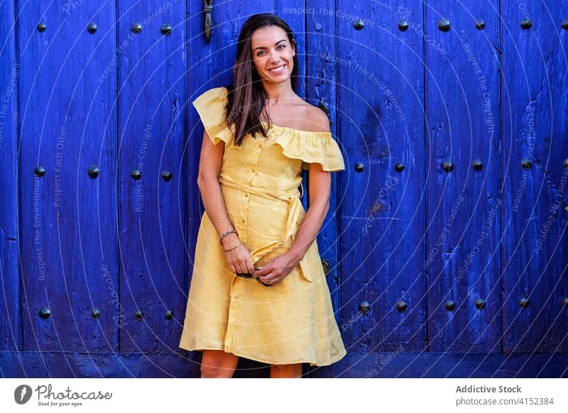 Fröhliche Frau in der Nähe von alten Toren in der Stadt Großstadt schlendern Wochenende Kleid schäbig hölzern Tür antik trendy historisch Gebäude fettarm ruhen