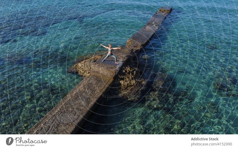 Frau macht Yoga in der Krieger-Pose Asana MEER ruhig friedlich virabhadrasana Harmonie üben Pier Wasser Gesundheit Küste idyllisch Meer Wellness Gelassenheit