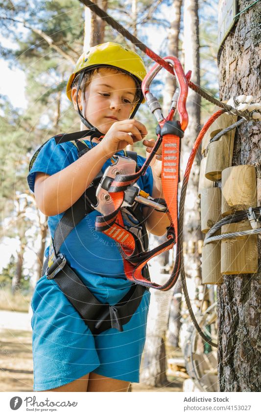 Süßer Junge im Abenteuerpark Park Gerät Karabiner Sicherheit Kabelbaum unterhalten Spaß haben Wochenende Sommer Seil behüten Schutzhelm extrem sicher Aktivität