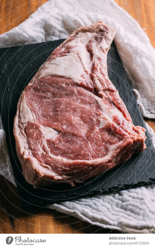 Ein Stück rohes Fleisch auf dem Tisch Rindfleisch Spielfigur Küche frisch Lebensmittel ungekocht natürlich Schiefer Holzplatte hölzern Feinschmecker Ernährung