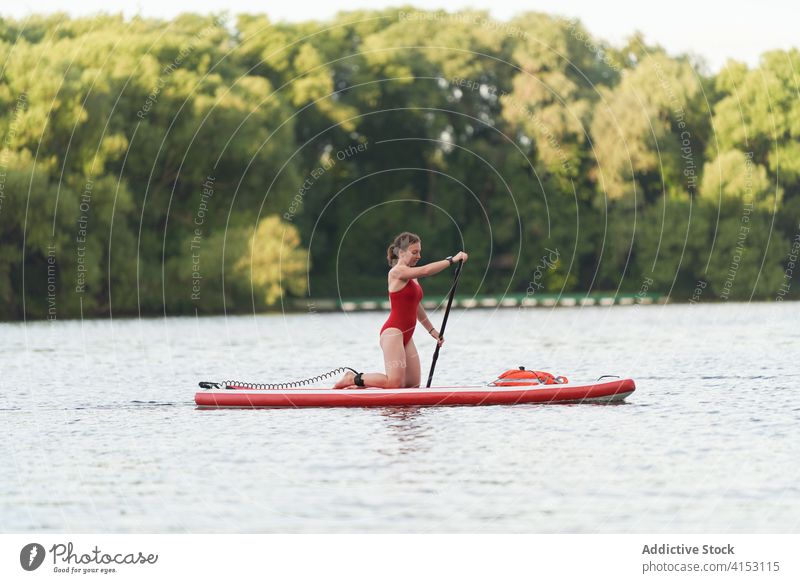 Weibliche Surferin schwimmt auf einem Paddelbrett Frau Reihe Brandung Surfbrett Fluss Brücke Großstadt Wasser Sommer Aktivität Sport Stadtbild Hobby Gerät