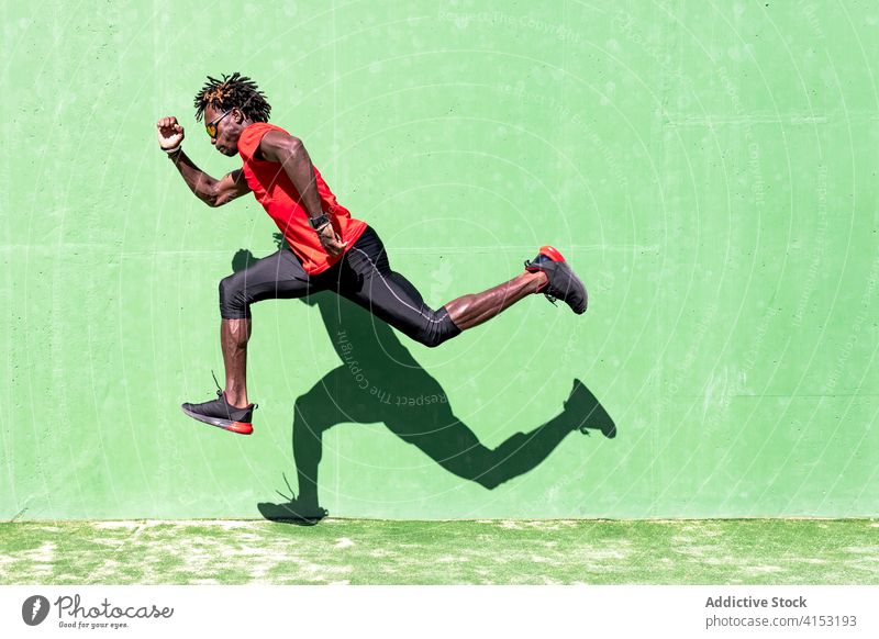 Fitter männlicher Sportler beim Training auf dem Sportplatz springen Mann Sommer intensiv passen Moment Übung ethnisch schwarz Afroamerikaner Sportkleidung