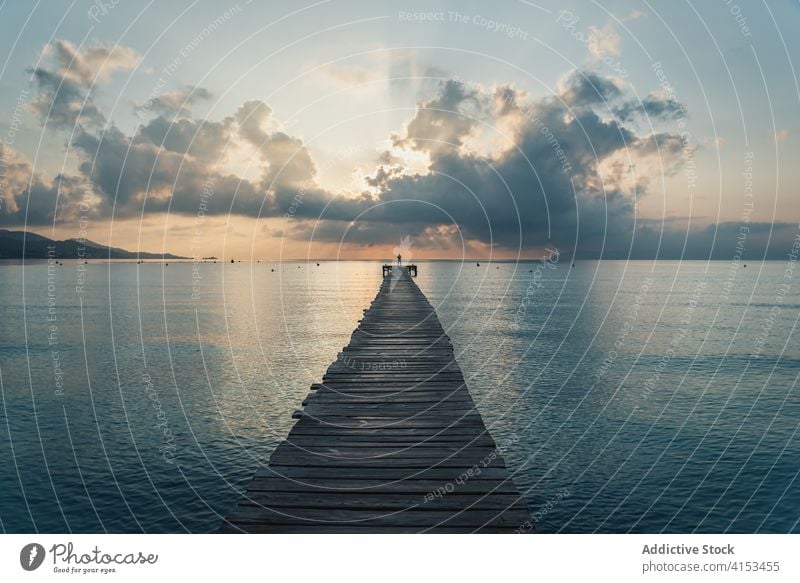 Anonyme Person steht auf einem Holzsteg im Meer bei Sonnenuntergang hölzern Pier MEER Meereslandschaft Wasser Kai wolkig dramatisch Playa de Alcudia Mallorca