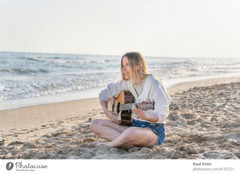 Junge kaukasische Frau spielt Akustikgitarre auf Sandstrand.Reise Lebensstil, Sommerurlaub Hintergrund mit Kopie Raum. Gitarre Spielen Strand Musik Lifestyle