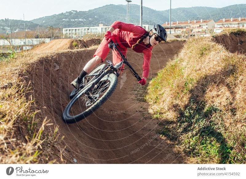 Radfahrerin mit Helm beim Üben auf der Trainingsstrecke Bahn Berge u. Gebirge Fahrrad praktizieren Frau Schutzhelm Testversion Trick Sportlerin Sportbekleidung