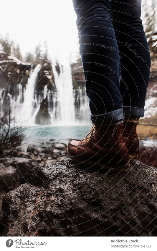 Anonyme Person an einem Wasserfall in einem verschneiten Bergwald an einem Wintertag Wald Schnee fließen Natur Landschaft Pool kalt strömen malerisch reisen