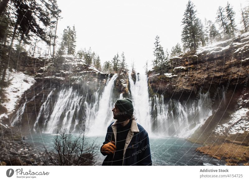 Männlicher Reisender auf Wasserfall in verschneiten bergigen Wald im Winter Tag Mann Schnee fließen Natur Person Landschaft Pool männlich kalt strömen malerisch