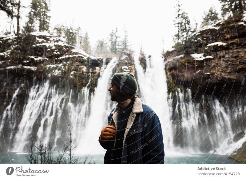 Männlicher Reisender auf Wasserfall in verschneiten bergigen Wald im Winter Tag Mann Schnee fließen Natur Person Landschaft Pool männlich kalt strömen malerisch