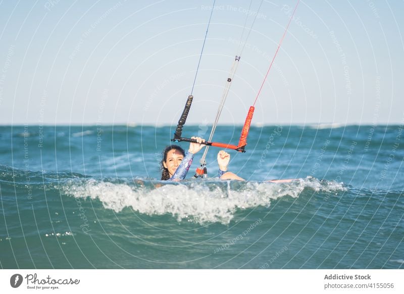 Weiblicher Kite-Surfer reitet auf dem Brett im Meer Milan Brandung Frau Mitfahrgelegenheit winken MEER platschen Sommer professionell Badeanzug passen Erholung