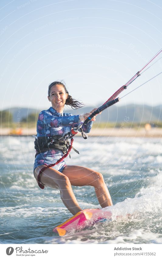 Weiblicher Kite-Surfer reitet auf dem Brett im Meer Milan Brandung Frau Mitfahrgelegenheit winken MEER platschen Sommer professionell Badeanzug passen Erholung