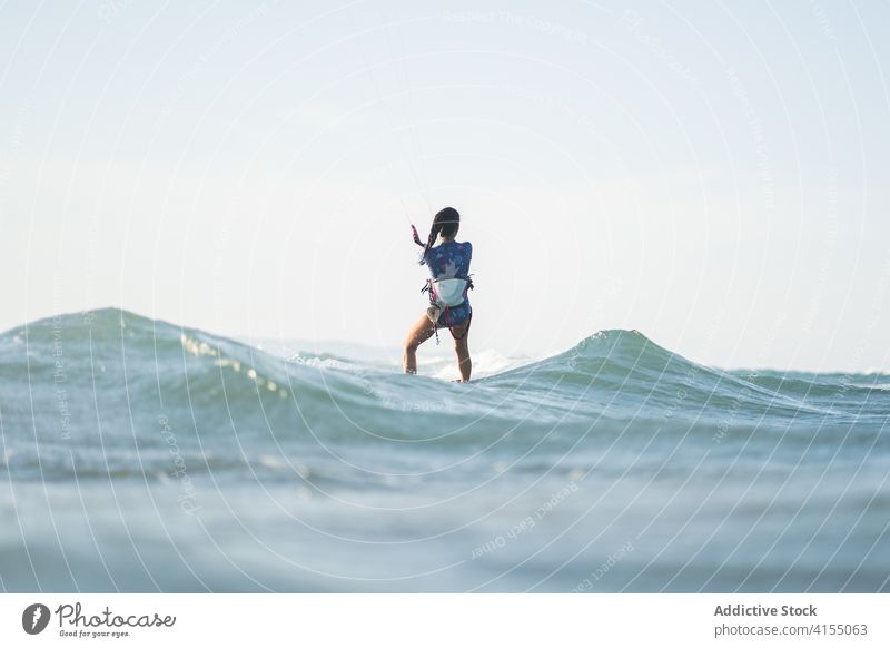 Weiblicher Kite-Surfer reitet auf dem Brett im Meer Milan Brandung Frau Mitfahrgelegenheit winken MEER platschen Sommer professionell Badeanzug passen Erholung