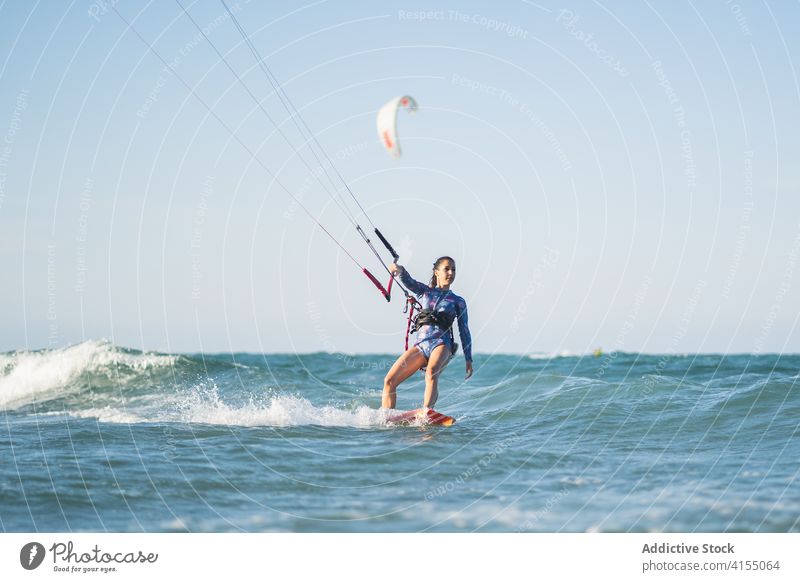 Weiblicher Kite-Surfer reitet auf dem Brett im Meer Milan Brandung Frau Mitfahrgelegenheit winken MEER platschen Sommer professionell Badeanzug passen Erholung