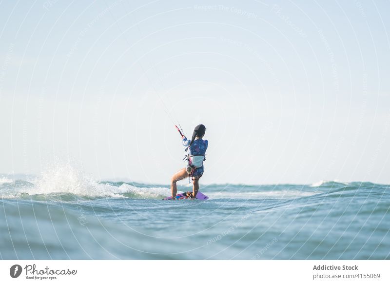 Weiblicher Kite-Surfer reitet auf dem Brett im Meer Milan Brandung Frau Mitfahrgelegenheit winken MEER platschen Sommer professionell Badeanzug passen Erholung