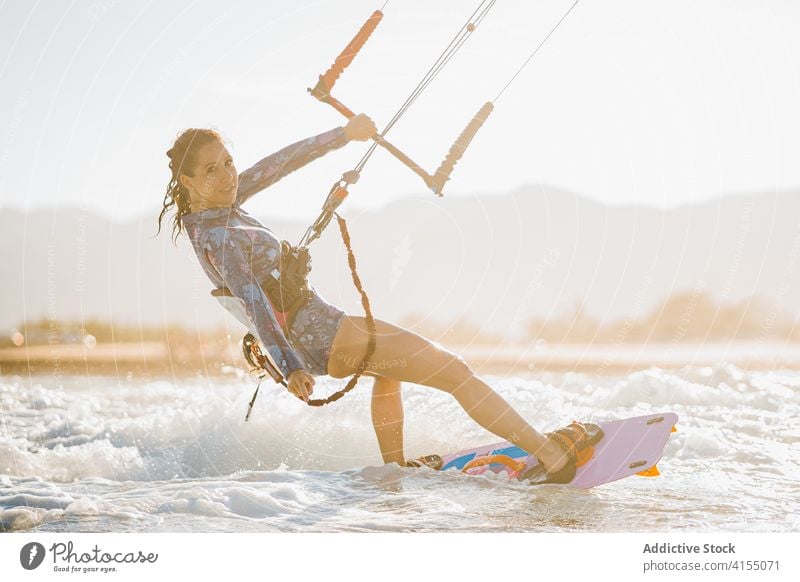 Weiblicher Kite-Surfer reitet auf dem Brett im Meer Milan Brandung Frau Mitfahrgelegenheit winken MEER platschen Sommer professionell Badeanzug passen Erholung