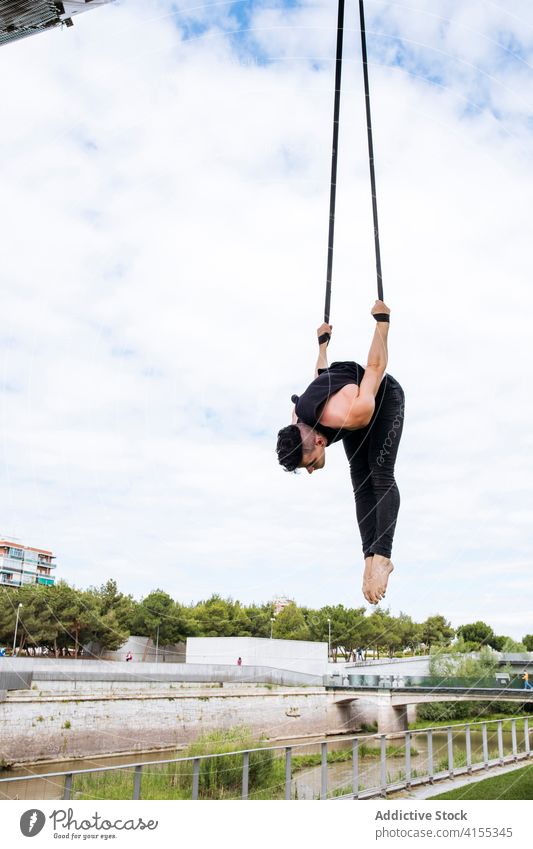 Flexibler Mann trainiert an Traggurten Antenne Gurt Turner Training gymnastisch hängen ausführen beweglich passen Park männlich Übung Energie Athlet Sport