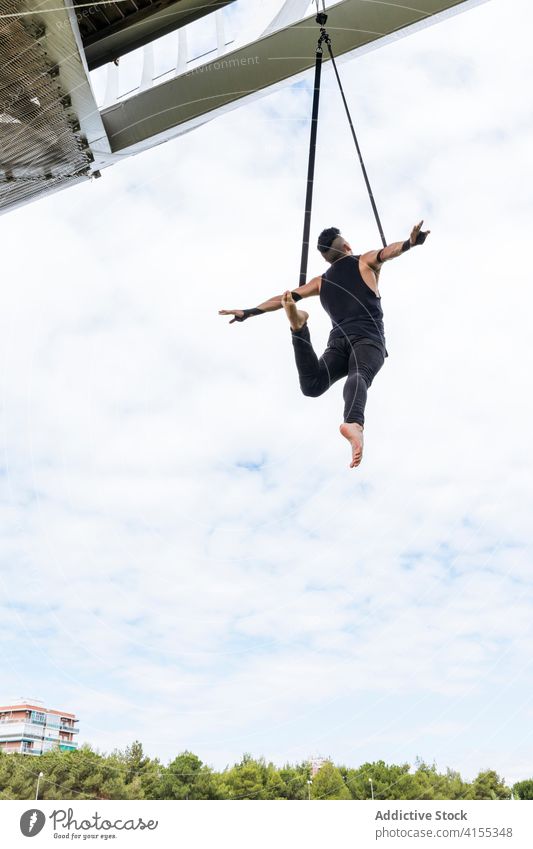 Flexibler Mann trainiert an Traggurten Antenne Gurt Turner Training gymnastisch hängen ausführen beweglich passen Park männlich Übung Energie Athlet Sport