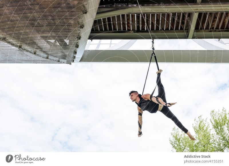 Flexibler Mann trainiert an Traggurten Antenne Gurt Turner Training gymnastisch hängen ausführen beweglich passen Park männlich Übung Energie Athlet Sport