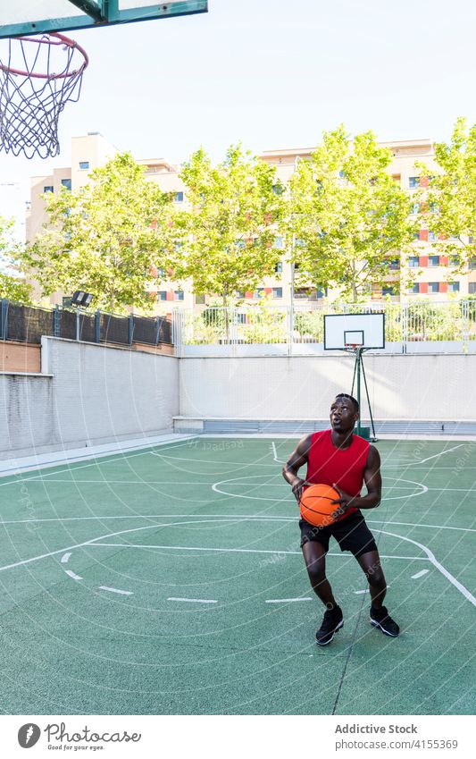 Konzentrierter schwarzer Mann spielt Basketball auf dem Platz Spieler spielen Ball Sportpark Spielplatz ernst Taktik Fokus männlich Afroamerikaner ethnisch