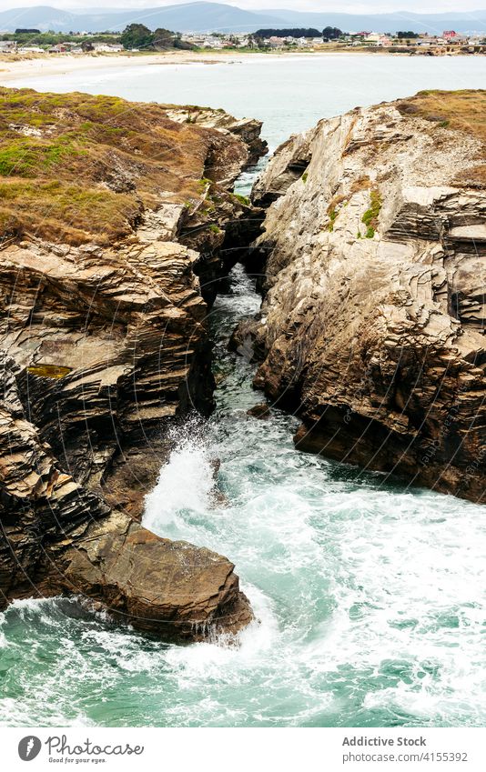 Felsige Klippe bei ruhiger See MEER Meereslandschaft türkis spektakulär Wasser Hügel Felsen Ufer malerisch bedeckt felsig Natur majestätisch wolkig rau Küste