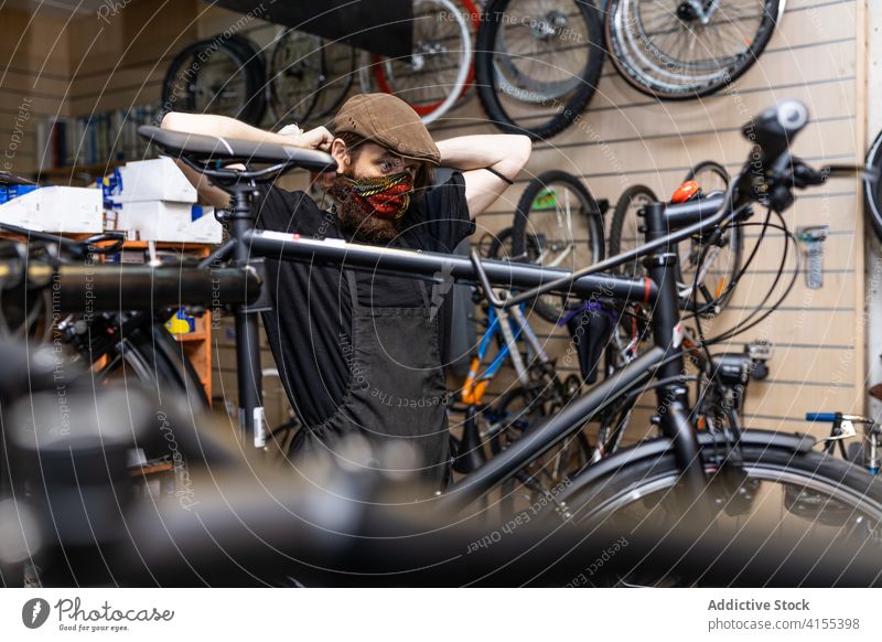 Mechaniker setzt Schutzmaske in der Werkstatt auf Mann Fahrrad Mundschutz behüten COVID angezogen Reparatur Flugzeugwartung Beruf Dienst männlich professionell