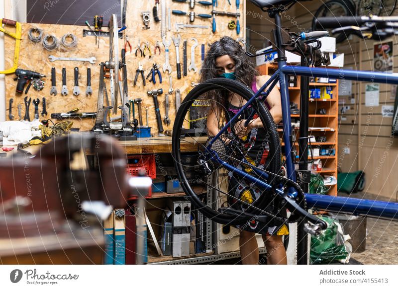 Frau repariert Fahrradrad in der Werkstatt Reparatur Mechaniker Rad Speiche fixieren Flugzeugwartung Beruf Dienst professionell Arbeit Job Wehen beschäftigt