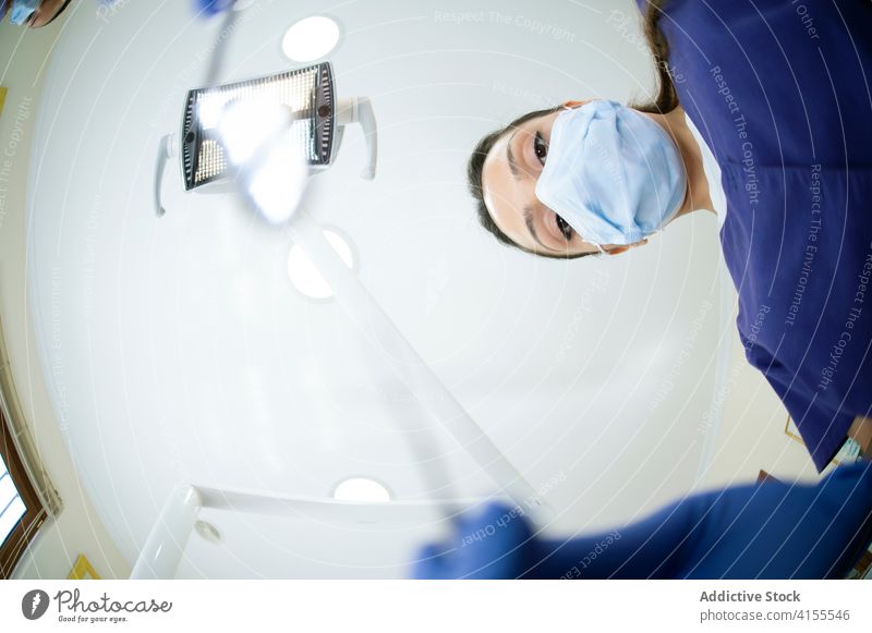 Ethnischer Zahnarzt bei der Arbeit Klinik Büro Spiegel asiatisch Gerät Mundschutz Uniform Behandlung medizinisch modern Arzt mündlich Hygiene Werkzeug