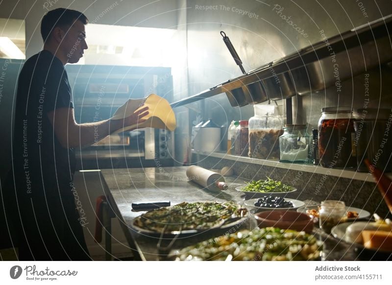 Chefkoch, der den Pizzateig dehnt und wendet Mann Küchenchef Teigwaren werfen Dehnung Flip Tisch Mehl Koch männlich Restaurant rund kreisen Tradition