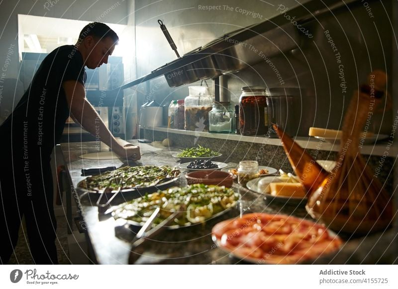 Koch rollt Teig für Gebäck aus Mann Küchenchef rollen Teigwaren Nudelholz Tisch Pizza Bestandteil Prozess männlich vorbereiten Dehnung frisch selbstgemacht