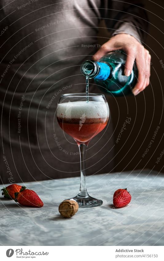 Crop-Frau gießt Getränk in Glas Alkohol eingießen trinken Erdbeeren Cocktail süß Tisch lecker frisch vorbereiten liquide geschmackvoll Prozess Bestandteil