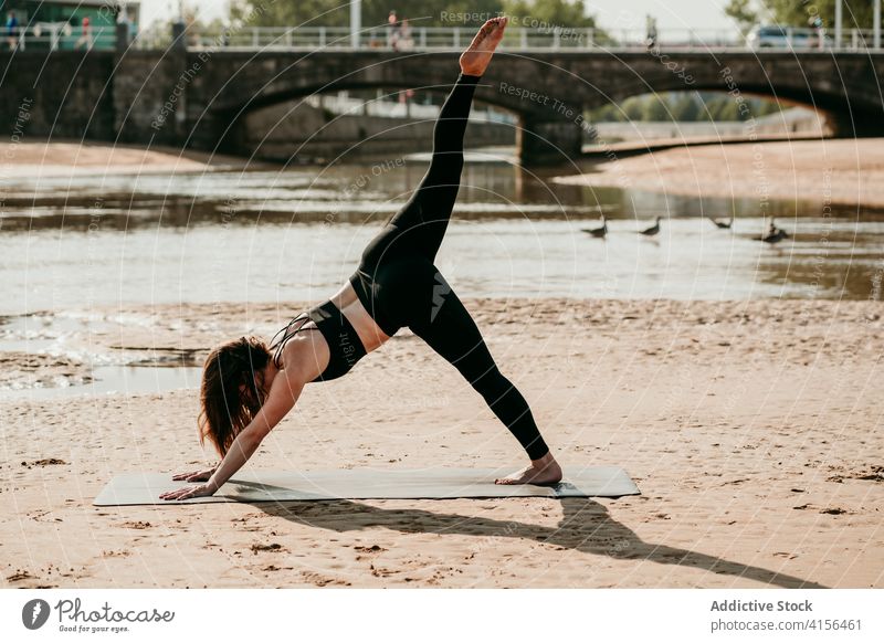 Schlanke Frau beim Yoga in Downward Facing Dog-Pose üben nach unten gerichtete Hundehaltung eka pada adho mukha svanasana Gleichgewicht schlank Zen Unterlage