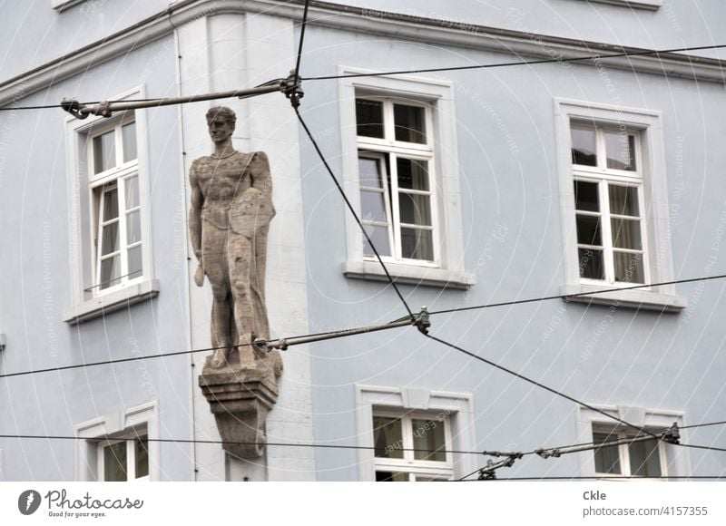 Hausmann Figur Statue Fenster Denkmal Leitungen Fensterrahmen Elektrik Gardinen Aussicht Ausblick Fassade Wand Mauer Außenaufnahme Farbfoto alt Tag Gebäude