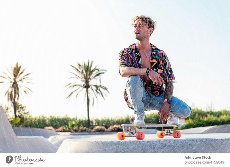 Hipster Skater sitzt auf Skateboard in der Nähe Rampe Mann Skatepark Stil Aktivität trendy ruhen jung männlich Schlittschuh Lifestyle modern tausendjährig