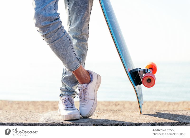 Crop-Skater auf modernem Skateboard in der Stadt Turnschuh Fuß Großstadt Schlittschuh Straße Sommer Stil Youngster cool Jeanshose urban Zeitgenosse aktiv