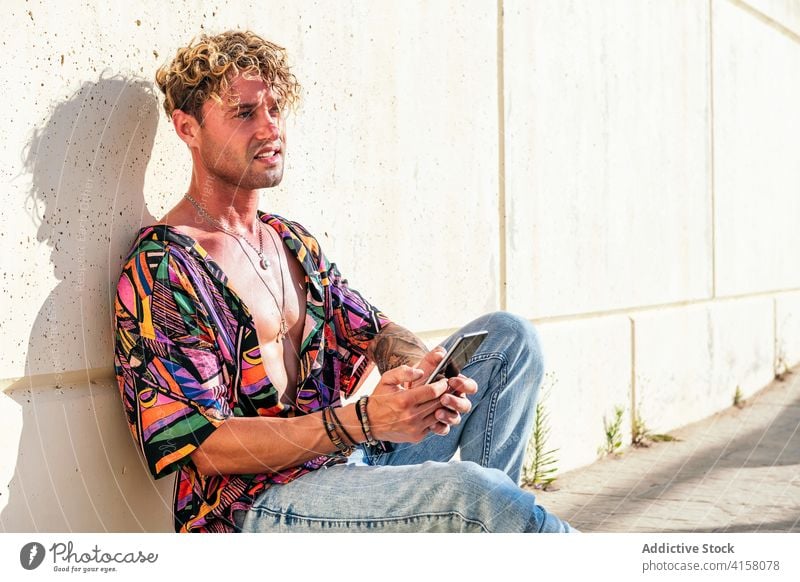 Männlicher Skater benutzt Smartphone im Park Hipster Skateboard Mann soziale Netzwerke jung trendy benutzend Nachricht männlich Rasen Mobile Gerät sonnig