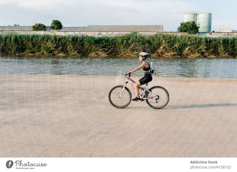 Glückliche Frau fährt Fahrrad auf unbefestigtem Weg Mitfahrgelegenheit Radfahrer Aktivität sportlich Natur Landschaft heiter Übung jung Schutzhelm Lifestyle