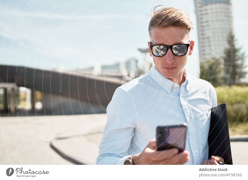 Moderner Mann mit stilvoller Sonnenbrille am Telefon in der Stadt Stil Smartphone urban modern selbstbewusst trendy jung männlich Mobile Kommunizieren Anschluss