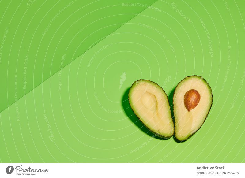 Frische Avocadohälften auf grünem Hintergrund Hälfte Frucht Scheibe geschnitten Spielfigur Samen frisch reif tropisch exotisch Farbe farbenfroh hell lebhaft