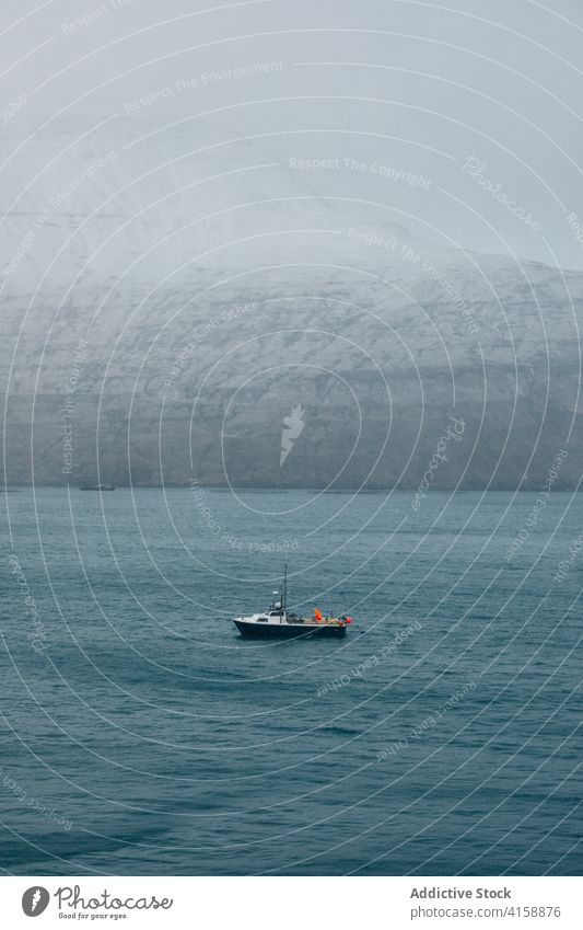 Fischkutter auf dem Meer in der Nähe des schneebedeckten Berges verschneite Fischerboot Tourismus Landschaft Fähre Himmel Natur Wasser blau reisen kalt Schnee