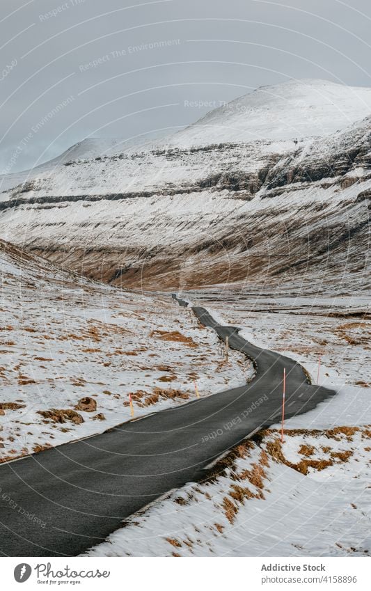 Straße in den Bergen auf den Färöer Inseln Asphalt Berge u. Gebirge Schnee Landschaft leer Natur Winter kalt Fahrbahn wolkig Hügel Ausflug Wetter Saison Weg