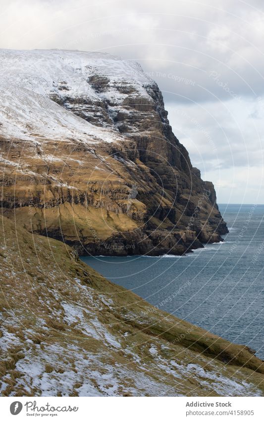 Felsenklippe in Meeresnähe auf den Färöer Inseln Klippe MEER Meereslandschaft Winter Schnee Saison kalt steil Gelände Färöer-Inseln felsig Landschaft