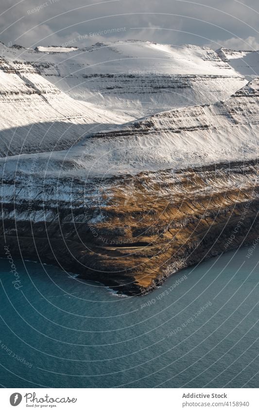 Felsenklippe in Meeresnähe auf den Färöer Inseln Klippe MEER Meereslandschaft Winter Schnee Saison kalt steil Gelände Färöer-Inseln felsig Landschaft