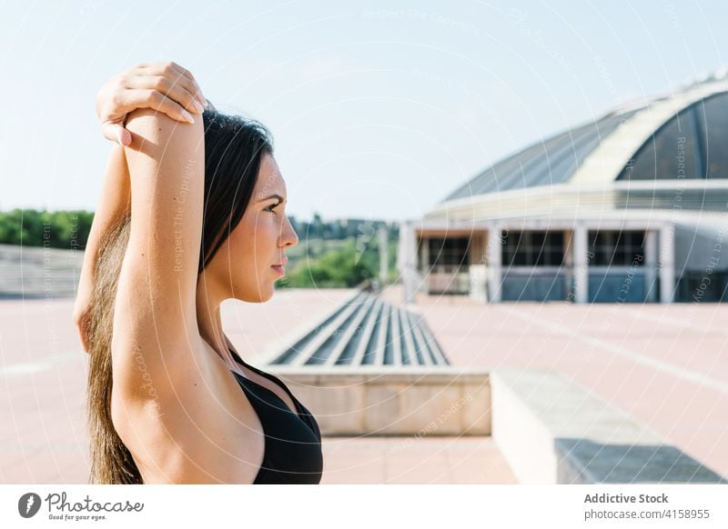 Sportliche Frau Aufwärmen vor dem Training auf der Straße Übung Dehnung Schulter urban Athlet passen Sportlerin jung schlank Fitness Sportbekleidung beweglich