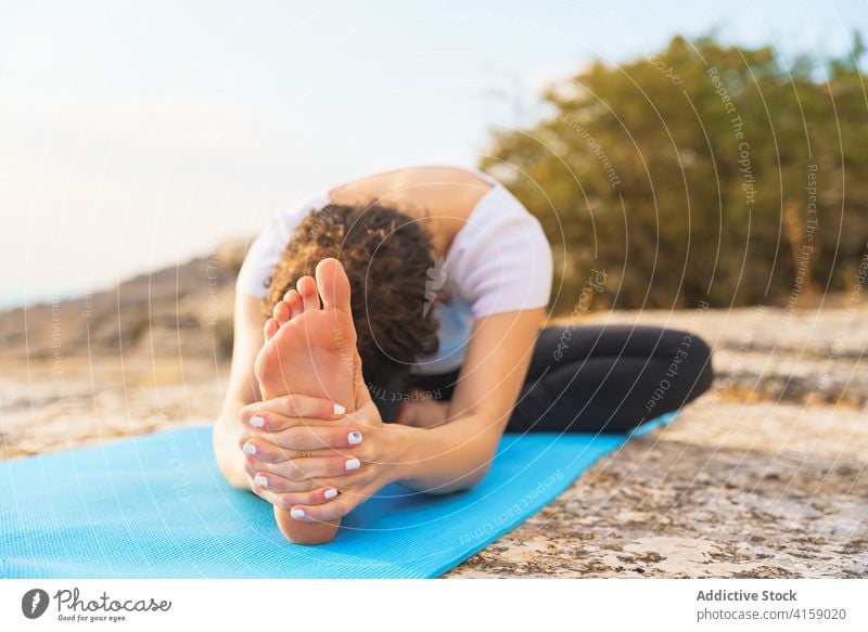 Flexible Frau beim Dehnen in einer Yoga-Asana in der Natur Von Kopf bis Knie sitzen weitergeben Wegbiegung Dehnung Janu Sirsasana beweglich Pose