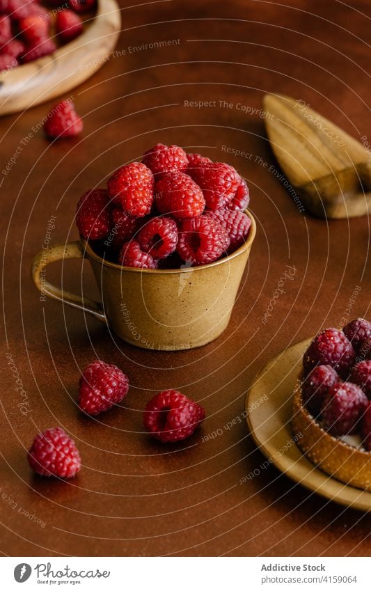 Tasse voller köstlicher reifer Himbeeren auf dem Tisch Vitamin süß lecker Törtchen Dessert frisch hölzern Beeren rot geschmackvoll duftig Leckerbissen Haufen