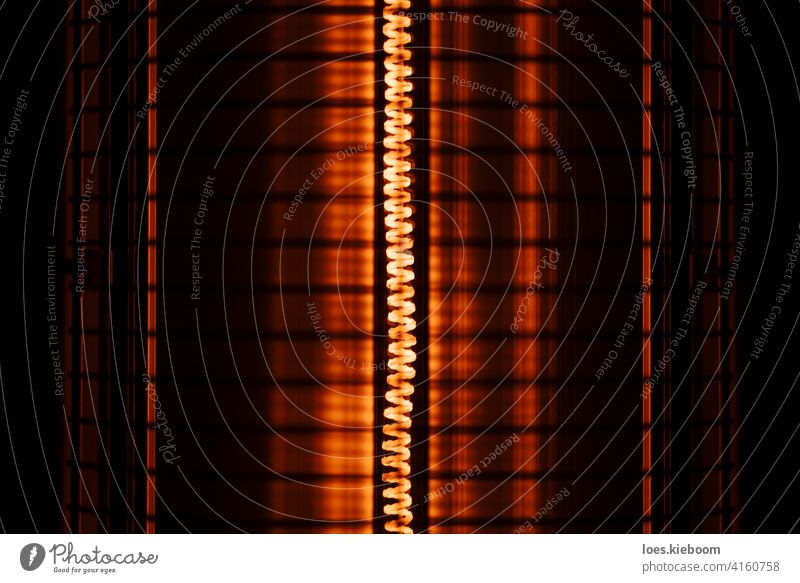 Nahaufnahme eines elektrischen Heizregisters mit Grillschutz Heizkörper Rolle warm heiß Licht rot Grillrost ineinander greifen Winter Temperatur Hintergrund